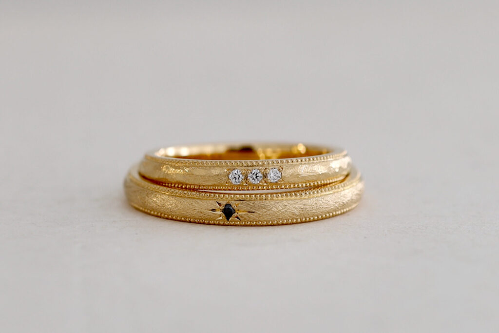 大阪と京都のオーダーメイドの結婚指輪　K20イエローゴールドの艶消し　３石繋げたダイヤモンド　ブラックダイヤモンドの星留め　ミルグレインのマリッジリング