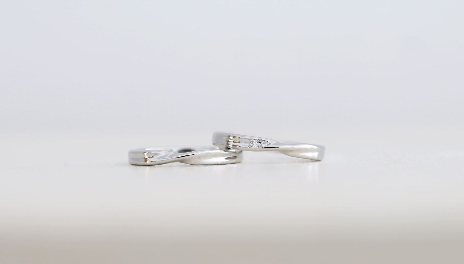 プラチナ950の結婚指輪「ayumi（あゆみ）」。ひねりのラインが重なり合うデザインに、2石のダイヤモンドをさりげなく留めたオーダーメイドのペアリング。