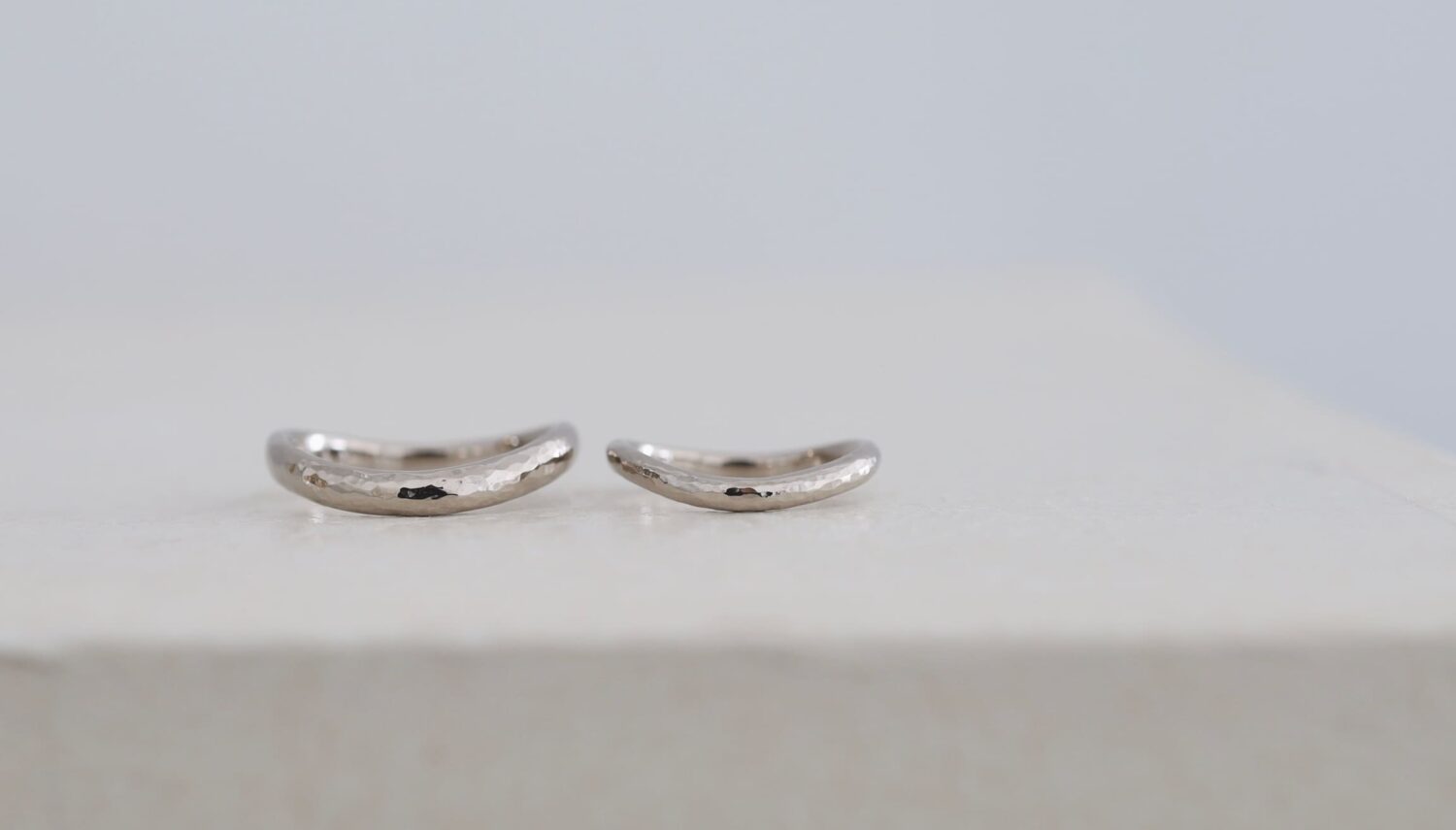 K18ホワイトゴールドの結婚指輪「glitter（グリッター）」。光を反射する凹凸のある表面と、ゆるやかなウェーブフォルムにアレンジしたオーダーメイドのペアリング。