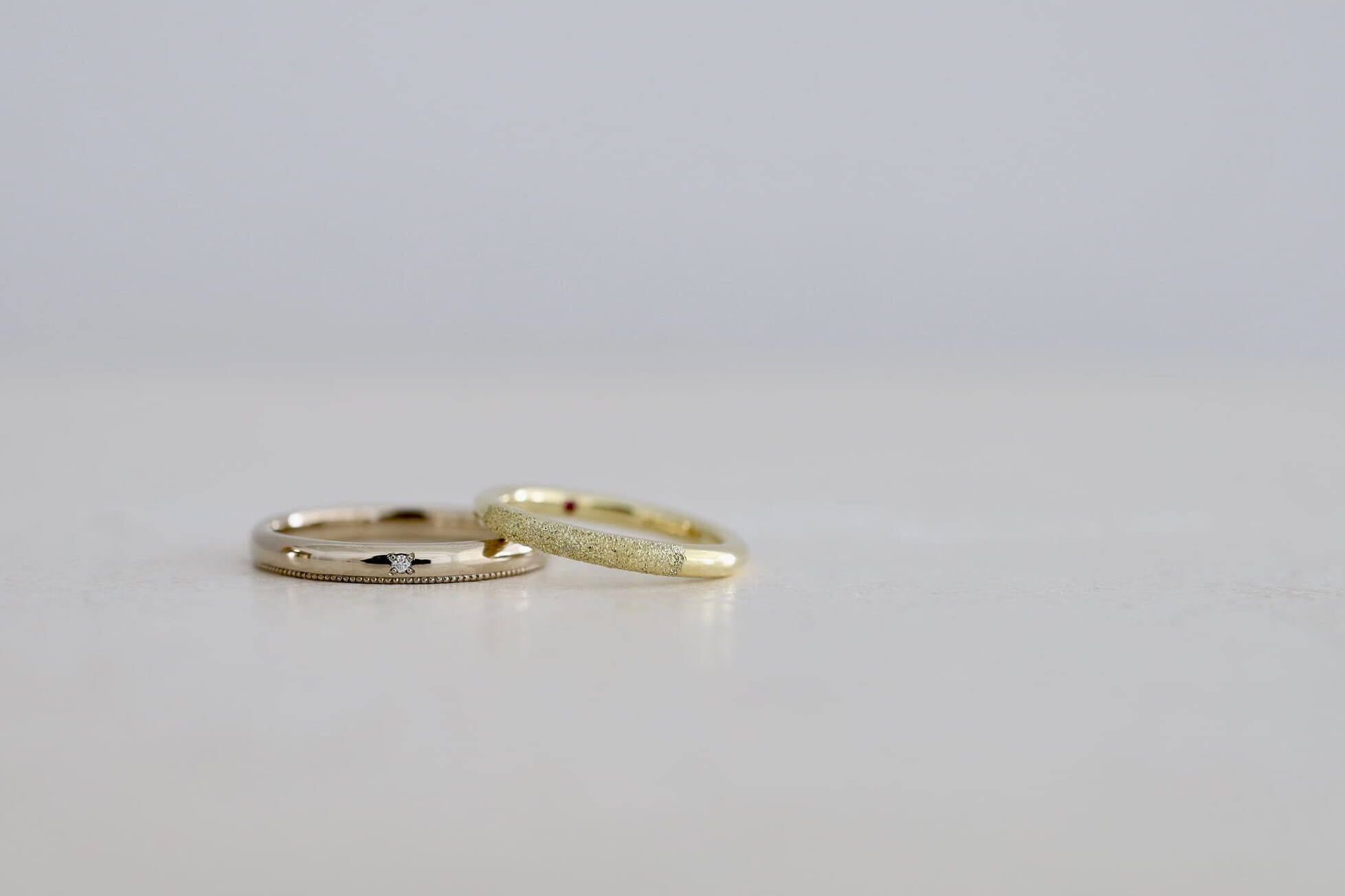 デザインの異なる二人の結婚指輪。K18ライムゴールドのdonutと、K18シャンパンゴールドにミルグレインを施したゴールドリング