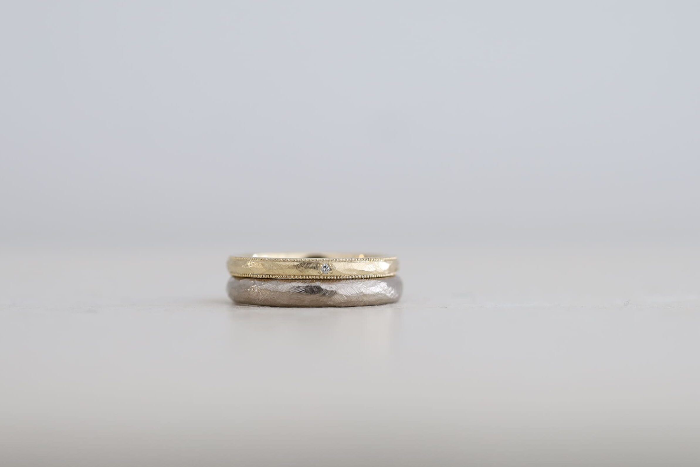 アンティーク加工を揃えた結婚指輪２本。片方には両側のミルグレインと一粒のダイヤモンドを添えたデザイン
